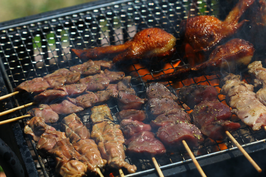 duck Skewers of meat cooking on a grill with smoke by Whole Meat TM
